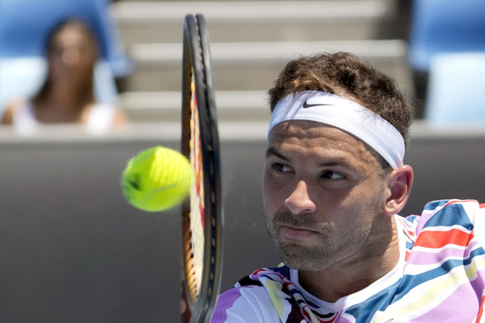 Grigor Dimitrov of Bulgaria plays a backhand return to Aslan Karatsev of Russia during their first round match at the Australian Open tennis championship in Melbourne, Australia, Tuesday, Jan. 17, 2023. (AP Photo/Dita Alangkara)