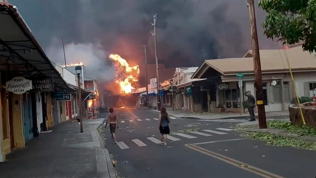 People watch as smoke and flames fill the air from raging wildfires on Front Street in downtown Lahaina, Maui.