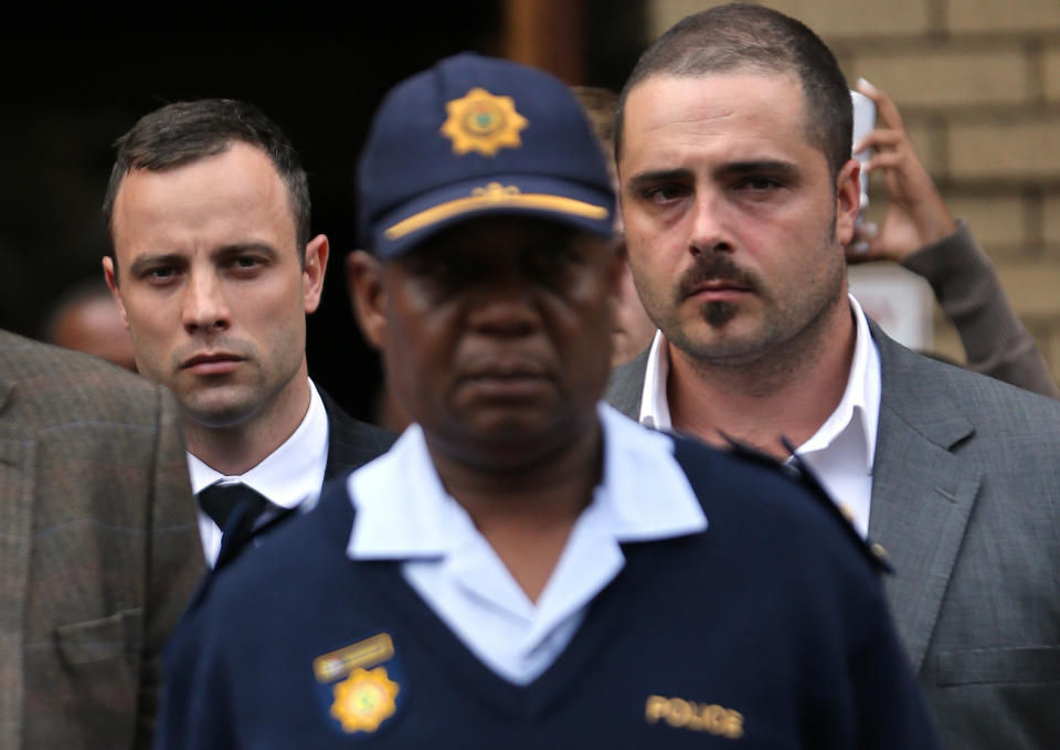 Oscar Pistorius, left, accompanied by police and unidentified relatives leaves the high court in Pretoria, South Africa, Wednesday, April 9, 2014. Pistorius is charged with murder for the 2013 shooting death of his girlfriend, Reeva Steenkamp. (AP Photo/Themba Hadebe)