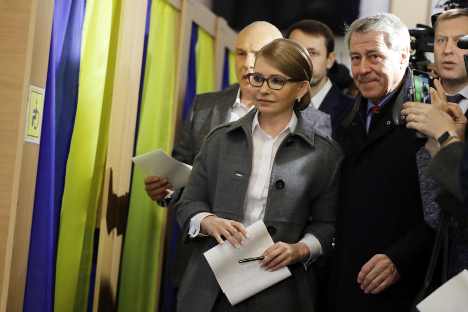 Former Ukrainian Prime Minister Yulia Tymoshenko, a candidate for the presidential election, center, holds her ballot for casting at a polling station during the presidential election in Kiev, Ukraine, Sunday, March 31, 2019. Ukrainians choose from among 39 candidates for a president they hope can guide the country of more than 42 million out of troubles including endemic corruption, a seemingly intractable conflict with Russia-backed separatists in the country's east and a struggling economy. (AP Photo/Sergei Grits)