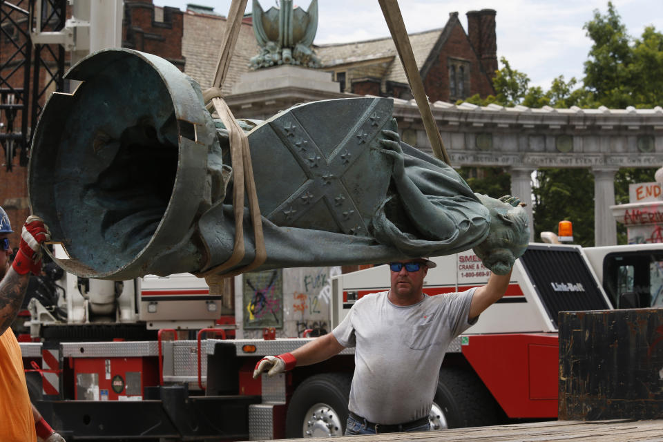 A workman guides the statue from the Jefferson Davis monument onto a flatbed truck after it was removed from its pedestal on Monument Ave. in Richmond, Va., Wednesday, July 8, 2020. The figure was atop a 65 foot tall Doric column topped by a bronze figure called "Vindicatrix," also known as "Miss Confederacy," is the work of Edward Virginius Valentine. (Bob Brown/Richmond Times-Dispatch via AP)
