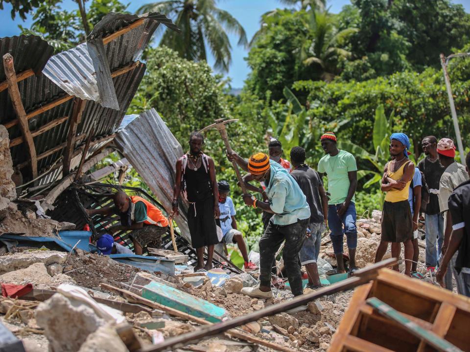 Locals search for victims in a home destroyed by an earthquake in Les Cayes (AP)