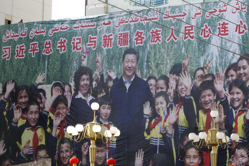 In this Aug. 31, 2018, photo, a propaganda poster showing Chinese President Xi Jinping with ethnic minority children and the slogan which reads "Party Secretary Xi Jinping and Xinjiang's multi ethnic residents united heart to heart" decorates the side of a building in Kashgar, western China's Xinjiang region. (AP Photo/Ng Han Guan)