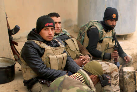 Members of the Lions of the Tigris, a group of Sunni Arab fighters and part of the Hashid Shaabi (Popular Mobilization Comimittee) warm themselves near a fire during a pause in a military operation against Islamic State militants in Shayyalah al-Imam, Iraq November 30, 2016. REUTERS/Thaier Al-Sudani