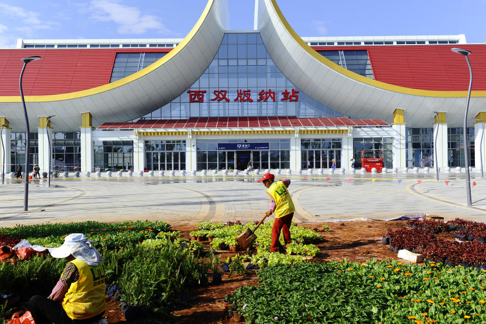 Landscapers work outside of a railway station in Xishuangbanna in southwestern China's Yunnan Province, Tuesday, Nov. 23, 2021. Laos, a nation of 7 million people wedged between China, Vietnam and Thailand, is opening a $5.9 billion Chinese-built railway that links China's poor southwest to foreign markets but piles on potentially risky debt. (Chinatopix via AP)