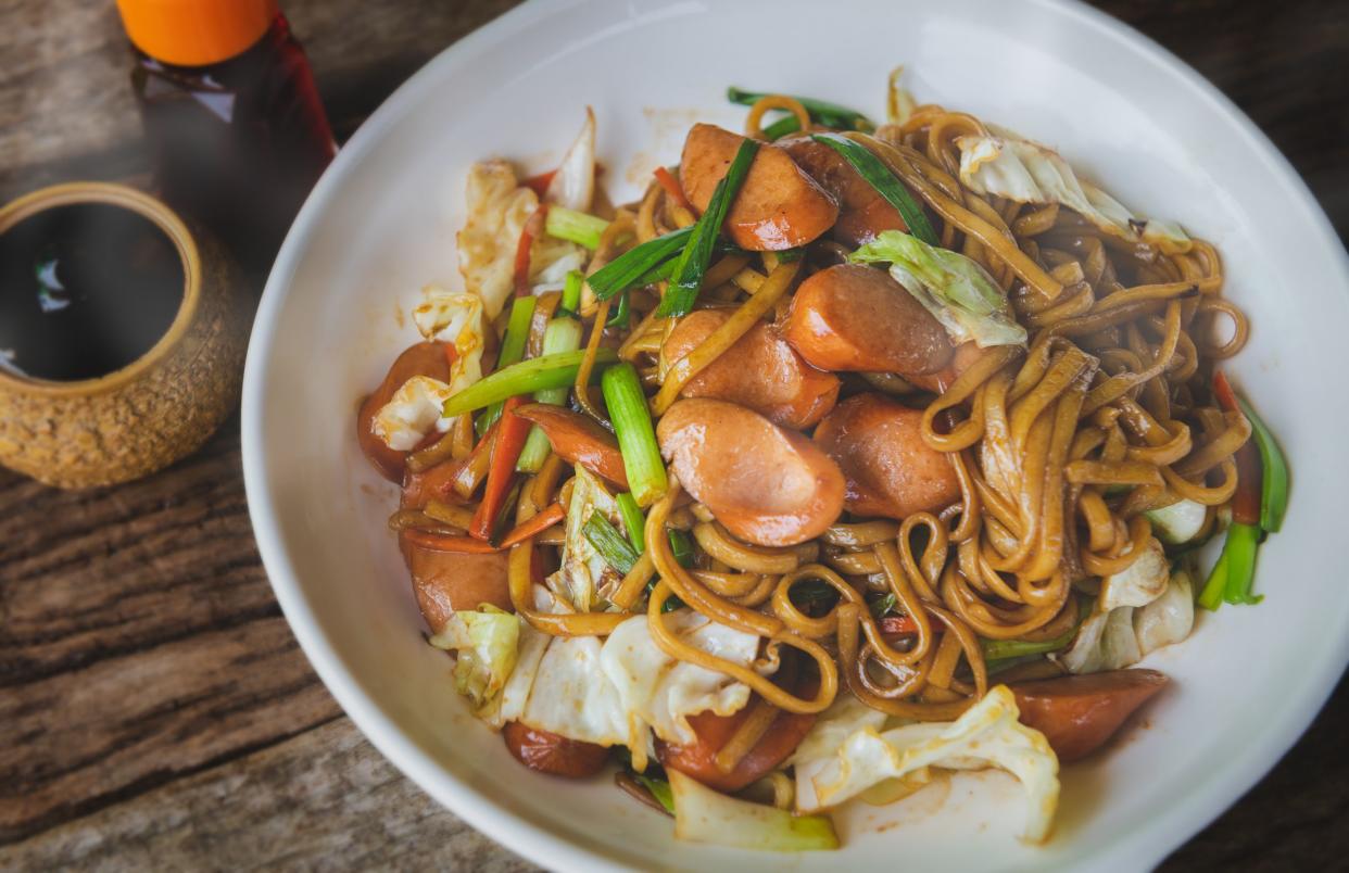 Yakisoba with sausage Japanese style fried noodle with sweet sauce in white plate with low sun lighting.