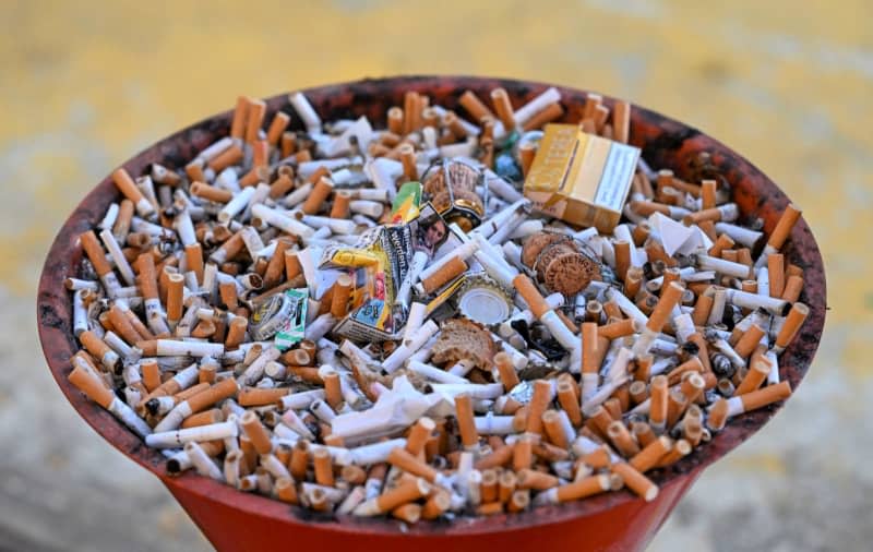 A bowl full of butts and packs of cigarettes. Jens Kalaene/dpa