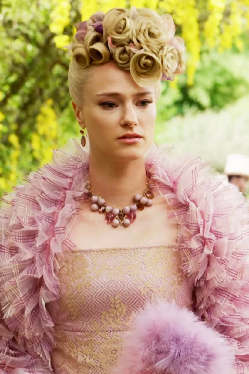 Jessica Madsen as Cressida  in a Victorian-style costume with an intricate ruffled shawl, beaded necklace, and lace gloves on a garden set