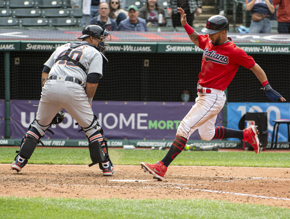 Cleveland Indians' Eddie Rosario, right, scores on a single by Franmil Reyes as Detroit Tigers' Wilson Ramos, left, waits for the ball during the eighth inning of a baseball game in Cleveland, Sunday, April 11, 2021. (AP Photo/Phil Long)