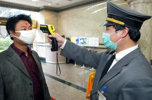 A security man checks the temperature of a man entering an office block in Shanghai on May 12, 2003. SARS infected about 8,000 people around the world, claiming most of its victims in Hong Kong, Taiwan, mainland China, Canada and Singapore