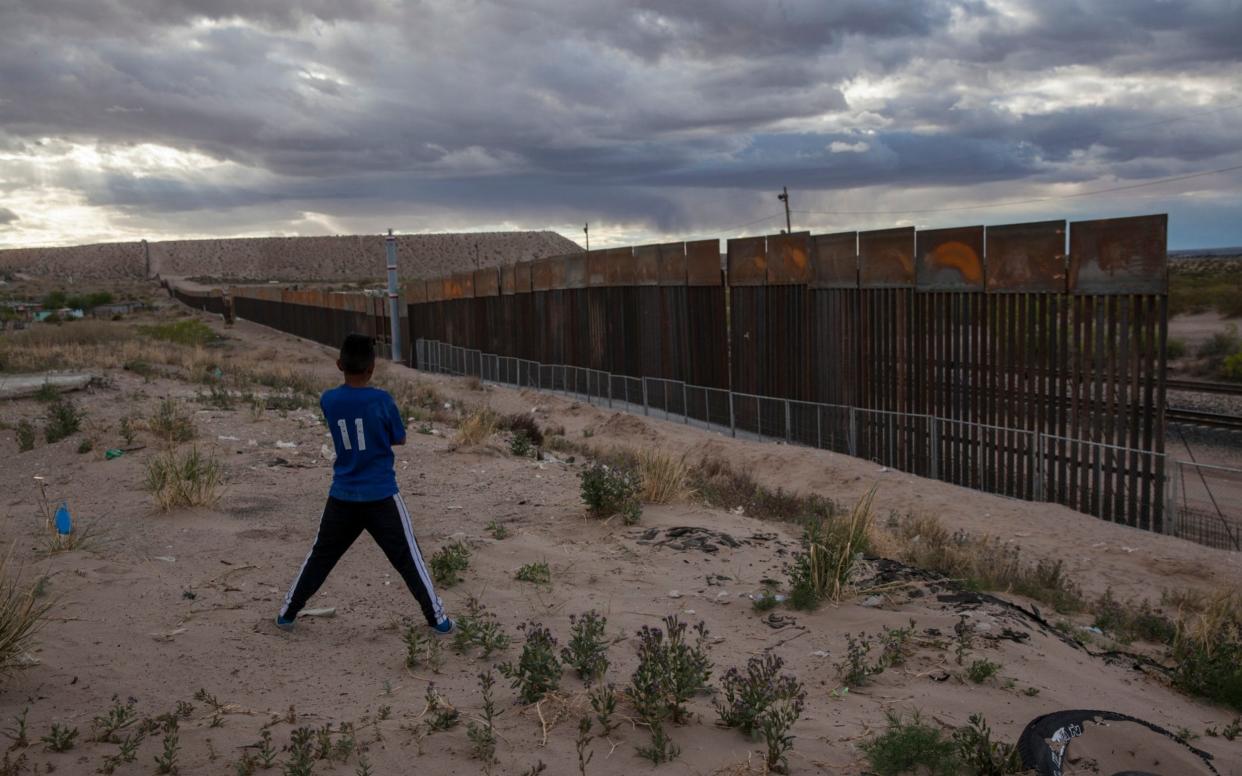 A youth looks at a new, taller fence being built along US-Mexico border, replacing the shorter, gray metal fence in front of it, in the Anapra neighborhood of Ciudad Juarez, Mexico - AP