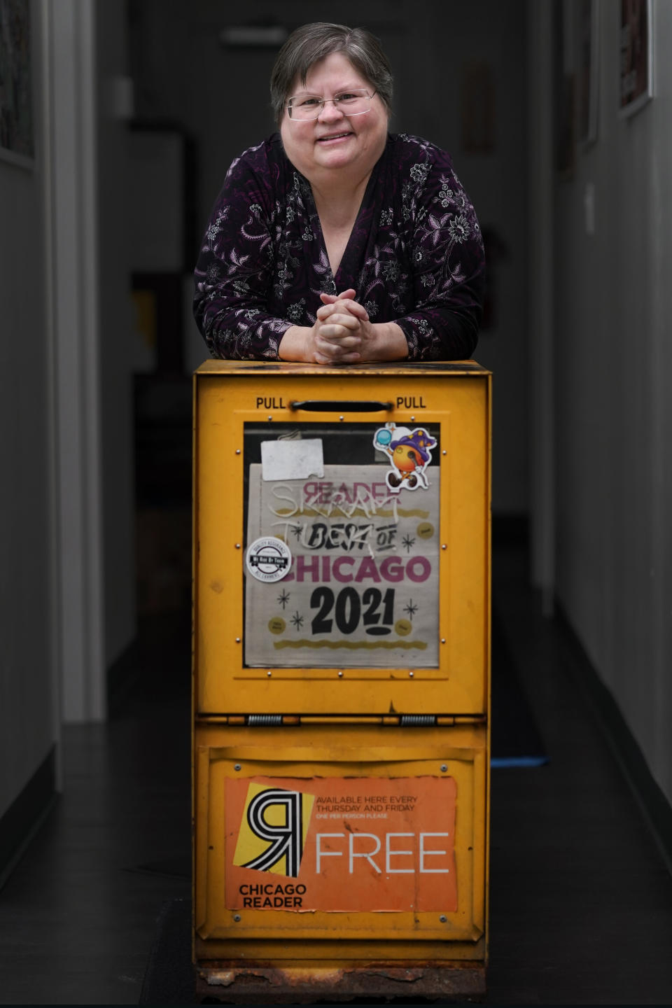 Tracy Baim, publisher of the Chicago Reader weekly newspaper stands for a portrait at her office with a weather beaten newspaper box Monday, May 9, 2022, in Chicago. The Reader is expected to become a nonprofit this month after the sale was nearly derailed over co-owner Leonard Goodman's column opposing COVID-19 vaccine requirements for children. Baim said editors asked to hire an independent fact-checker to vet the column. Baim said she and her co-publisher then met with Goodman and discussed options, but "it was very clear he didn't like any" of their proposals. (AP Photo/Charles Rex Arbogast)