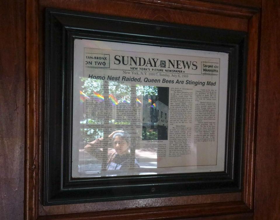In this Friday, June 14, 2019, photo, a framed newspaper clipping, right, hangs near the entrance of the Stonewall Inn in New York, headlining the 1969 riots that followed a police raid of the bar. Some of the coverage of rioting was itself a source of the fury that led Stonewall to become a synonym for the fight for gay rights.(AP Photo/Bebeto Matthews)