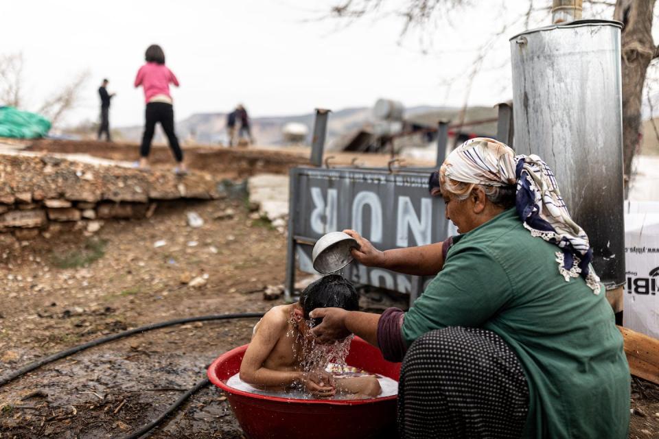 A woman in Yaylakonak village in Turkey – destroyed by the February 2023 earthquake – bathes a child outside. <a href="https://media.gettyimages.com/id/1476762841/photo/earthquake-in-türkiye.jpg?s=612x612&w=gi&k=20&c=yle-V4HrMwKuEXq-7xf1YDjmPBtQN35MoDPWDImySx8=" rel="nofollow noopener" target="_blank" data-ylk="slk:Ugur Yildirim/dia images via Getty Images;elm:context_link;itc:0;sec:content-canvas" class="link ">Ugur Yildirim/dia images via Getty Images</a>
