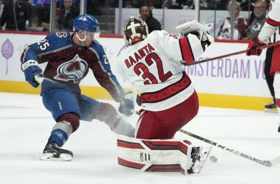 Carolina Hurricanes goaltender Antti Raanta, right, clears the puck next to Colorado Avalanche right wing Logan O'Connor during the first period of an NHL hockey game Saturday, Nov. 12, 2022, in Denver. (AP Photo/David Zalubowski)