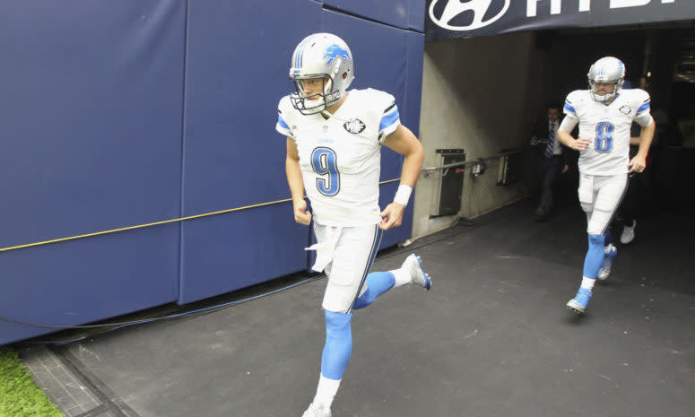 Detroit Lions quarterbacks Matthew Stafford and Dan Orlovsky run onto the field.