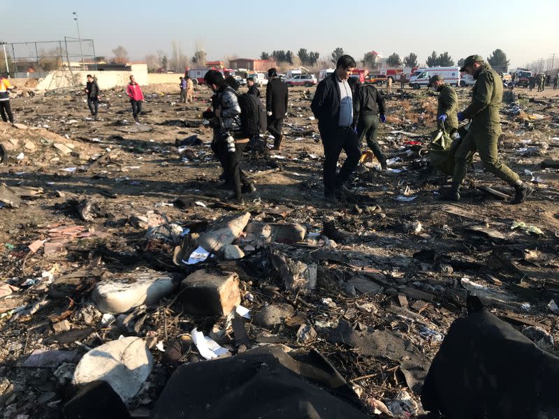 Rescue team members with people check the debris from a plane crash belonging to Ukraine International Airlines after take-off from Iran's Imam Khomeini airport, on the outskirts of Tehran