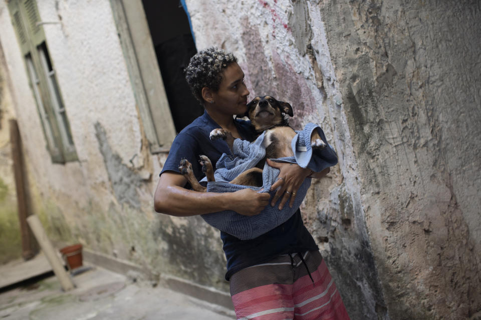 Transgender Micaelo Lopes carries pet dog, Stonewall, wrapped in a towel after a bath at the squat known as Casa Nem, occupied by members of the LGBTQ community who are in self-quarantine as a protective measure against the new coronavirus, in Rio de Janeiro, Brazil, Wednesday, July 8, 2020. “We have increased our activities to help our psychological state,” said Lopes, a 22-year-old transgender man. “It’s a very tense moment where we are waiting to see what’s going to happen afterward, without really knowing.” (AP Photo/Silvia Izquierdo)