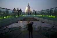 Tourists walk across the Millennium Bridge near the Tate Modern in London March 12, 2012.