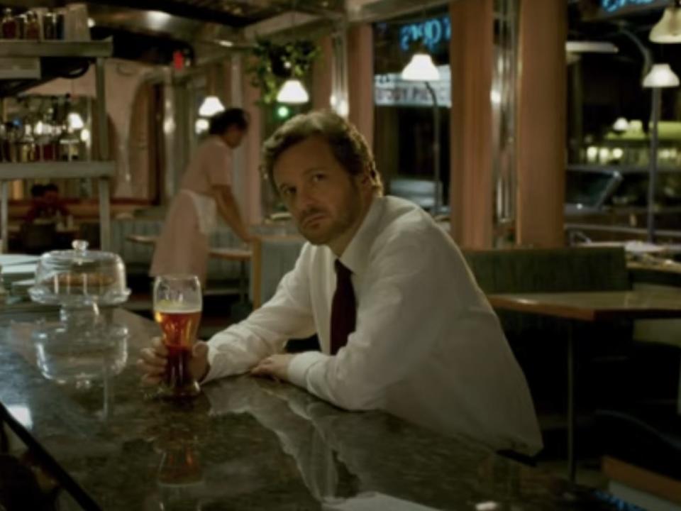 Colin Firth sitting in a diner with his hand on a glass in "Devil's Knot."