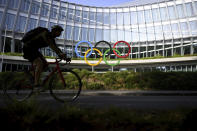 A cyclist rides past the Olympic House, headquarters of the International Olympic Committee (IOC) at the opening of the executive board meeting of the International Olympic Committee (IOC), at the Olympic House, in Lausanne, Switzerland, Tuesday, June 20, 2023 (Laurent Gillieron/Keystone via AP)