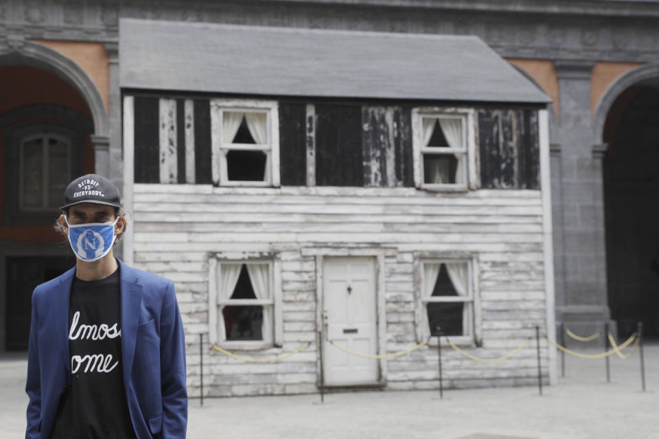 Artist Ryan Mendoza stands in front of the house of U.S. civil rights campaigner Rosa Parks, which he rebuilt for public display, in Naples, Italy, Tuesday, Sept. 15, 2020. The rundown, paint-chipped Detroit house where Parks took refuge after her famous bus boycott is on display in a setting that couldn't be more incongruous: the imposing central courtyard of the 18th century Royal Palace. (AP Photo/Gregorio Borgia)