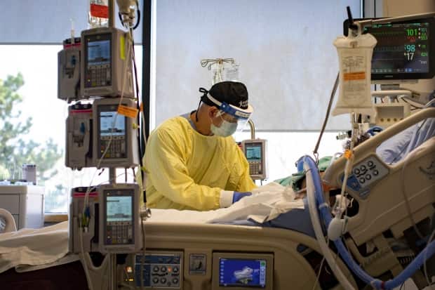 Registered nurse Jose Pasion tends to a patient in the intensive care unit at Scarborough Health Network’s Centenary Hospital. (Evan Mitsui/CBC - image credit)
