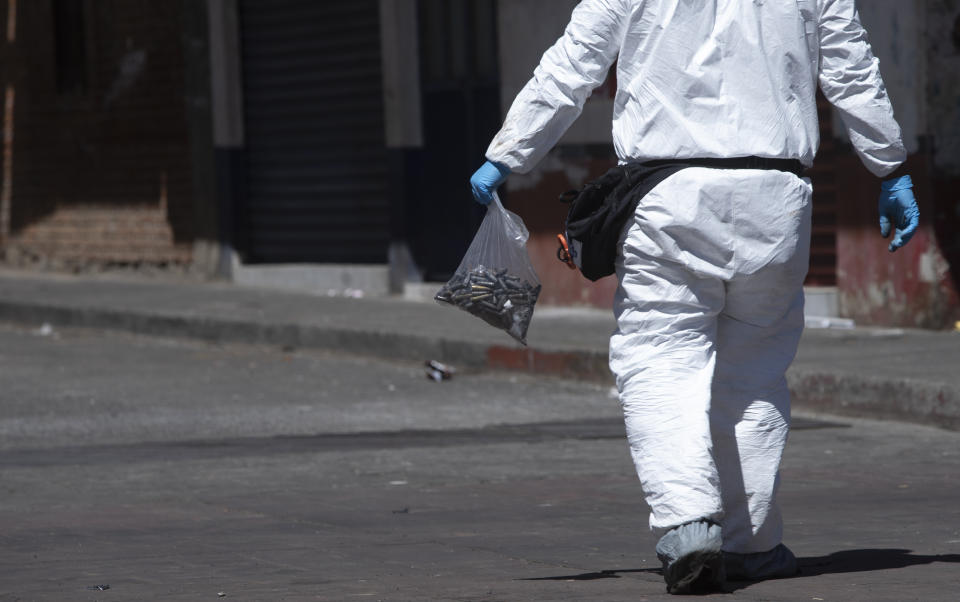 A forensics investigator walks the scene of a massive shootout in Parangaricutiro, Mexico,Thursday, March 10, 2022. Authorities in the avocado-growing zone of western Mexico said five suspected drug cartel gunmen have been killed in a massive firefight between gangs. ( AP Photo/Armando Solis)