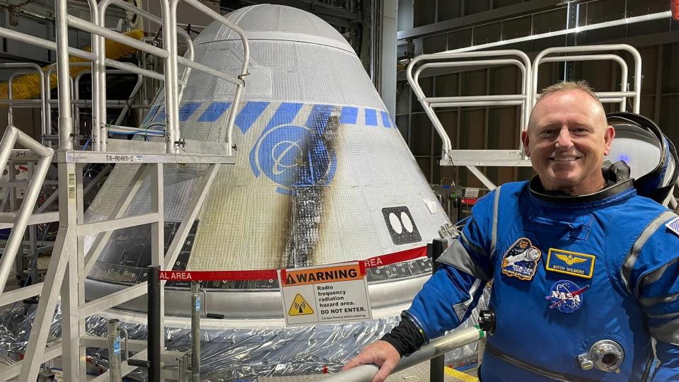 un astronaute en combinaison spatiale à côté d'un vaisseau spatial en forme de cône dans une installation