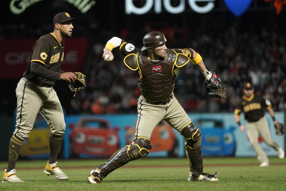 San Diego Padres pitcher Robert Suarez, left, watches as catcher Brett Sullivan throws out San Francisco Giants' Michael Conforto at first base during the eighth inning of a baseball game in San Francisco, Wednesday, Sept. 27, 2023. (AP Photo/Jeff Chiu)