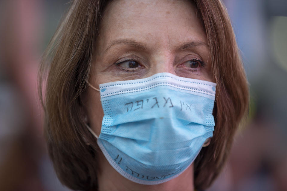 An Israeli protester wears a face mask amid concerns over the country's coronavirus outbreak, written in Hebrew it reads "there is no epidemic, there is dictatorship", during the "Black Flag" protest against Israeli Prime Minister Benjamin Netanyahu in Tel Aviv, Israel, Monday, July 6, 2020. The protesters oppose a new draft bill that would allow the government to bypass the legislative process in the Knesset in order to impose virus restrictions more quickly and with fewer hurdles. The protesters see the bill as undemocratic. (AP Photo/Oded Balilty)