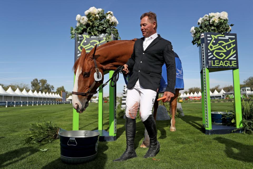 Professional show jumper Kyle King holds back "Etalon" from eating carrots while being interviewed during the Major League Show Jumping Tour at Desert International Horse Park in Thermal, Calif., on Thursday, December 1, 2022.
