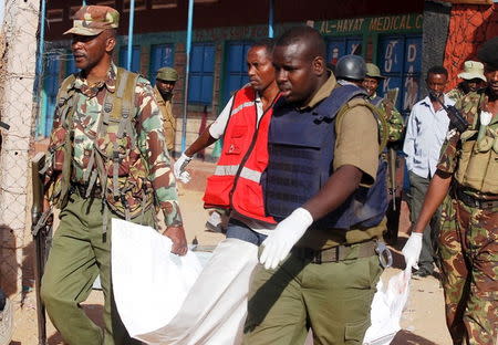 Kenyan police officers and Kenya Red Cross workers carry the body of a man killed during an overnight attack on a residential complex in Mandera town, Kenya, at the border with Somalia July 7, 2015. REUTERS/Stringer