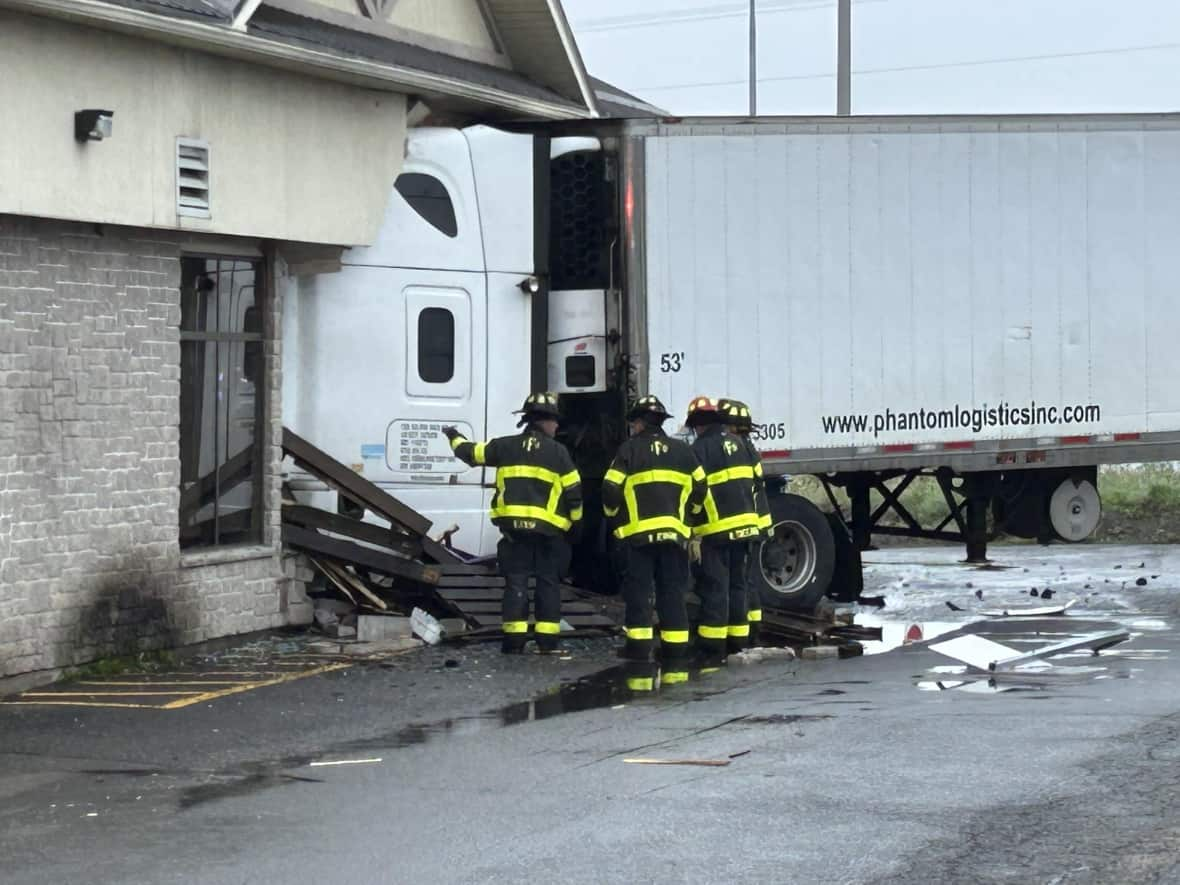 A tractor-trailer truck collided with a building, disrupting traffic at the roundabout in uptown Fredericton on Wednesday morning. (Jennifer Sweet/CBC - image credit)