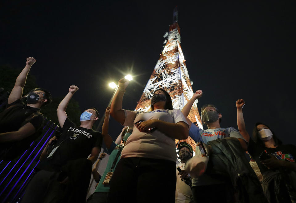 Employees and supporters of ABS-CBN raise their clenched fist as they sing outside their headquarters in Quezon City, Philippines Friday July 10, 2020. Philippine lawmakers voted Friday to reject the license renewal of the country's largest TV network ABS-CBN, shutting down a major news provider that had been repeatedly threatened by the president over its critical coverage. (AP Photo/Aaron Favila)