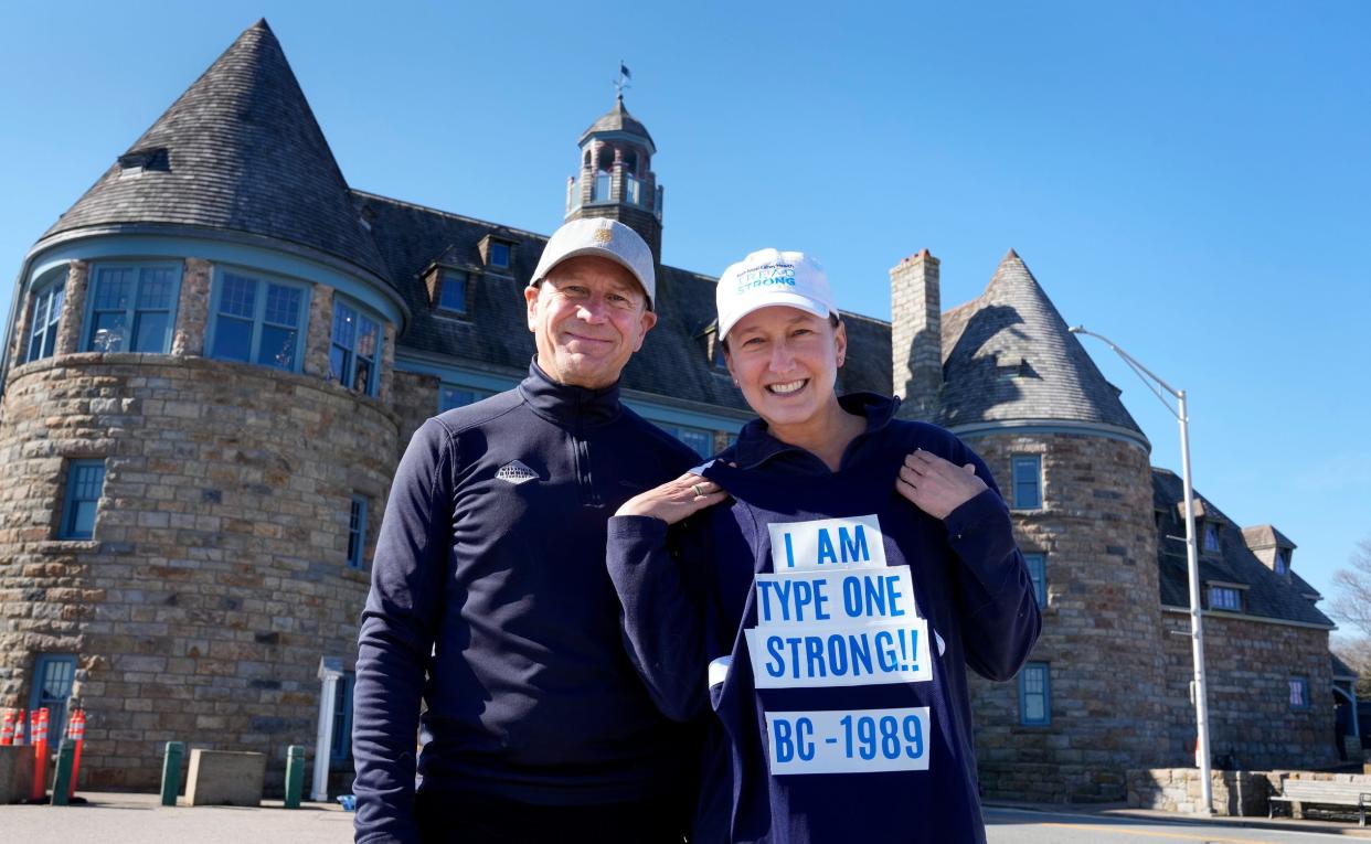 Jim and Michele Gilbert stop during a run along a sea wall in Narragansett. Michele is holding the singlet (with message on the back) that she'll be wearing Monday when the couple and their two daughters run the Boston Marathon.