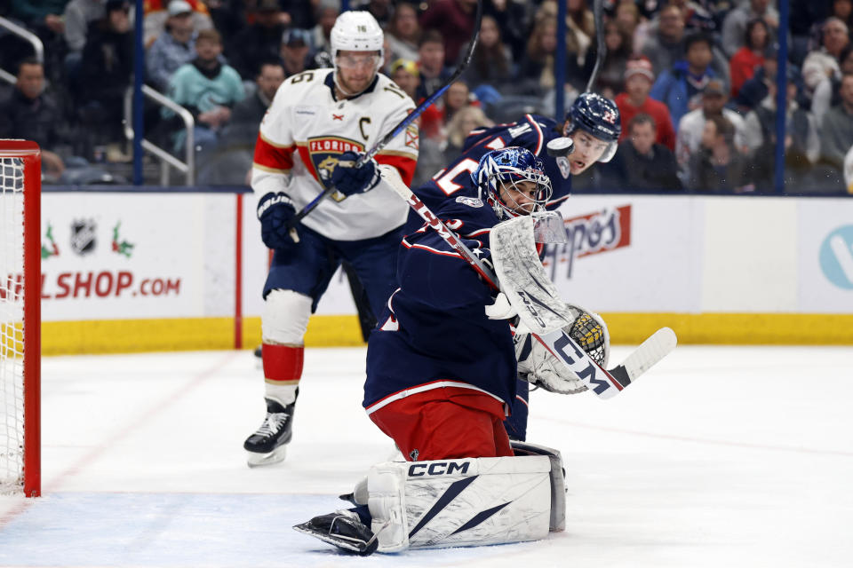 Columbus Blue Jackets goalie Jet Greaves, center, makes a stop between Blue Jackets defenseman Jake Bean, right, and Florida Panthers forward Brendan Gaunce during the first period of an NHL hockey game in Columbus, Ohio, Sunday, Dec. 10, 2023. (AP Photo/Paul Vernon)