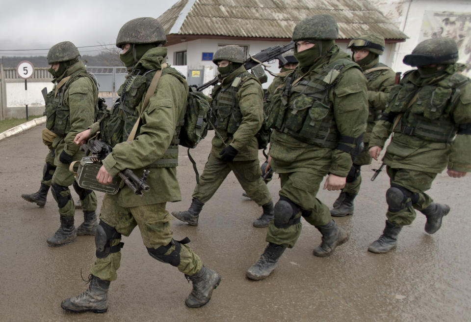 FILE - Pro-Russian soldiers march outside an Ukrainian military base in Perevalne, Crimea, Thursday, March 20, 2014. The Crimean Peninsula's balmy beaches have been vacation spots for Russian czars and has hosted history-shaking meetings of world leaders. And it has been the site of ethnic persecutions, forced deportations and political repression. Now, as Russia’s war in Ukraine enters its 18th month, the Black Sea peninsula is again both a playground and a battleground. (AP Photo/Vadim Ghirda, File)