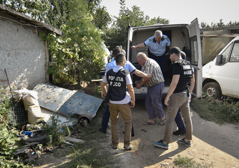 Police officers escort Gheorghe Dinca, the suspect in the case of rape and murder of a 15 year-old girl, to his home in Caracal, southern Romania, for further investigations, Saturday, July 27, 2019. Thousands of people took part Saturday evening in Bucharest in a march protesting the handling of the case, blaming Romanian officials for negligence, incompetence and a lack of empathy. (AP Photo/Bogdan Danescu)