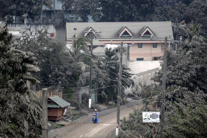 A motorcycle rider moves on an ash covered road, following the eruption of Taal Volcano, in Tagaytay