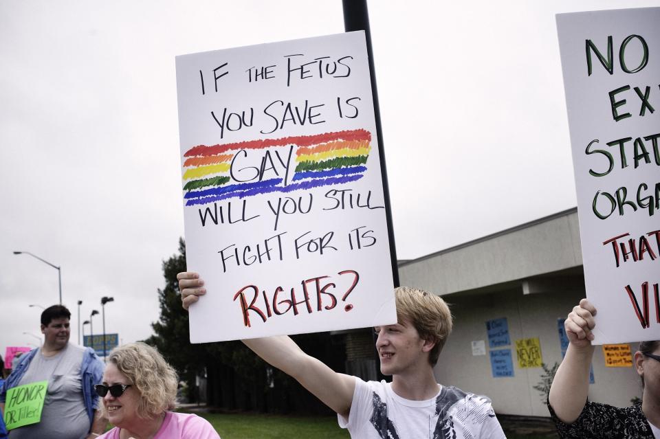 A demonstrator holds a sign reading "If the fetus you save is gay, will you still fight for its rights"