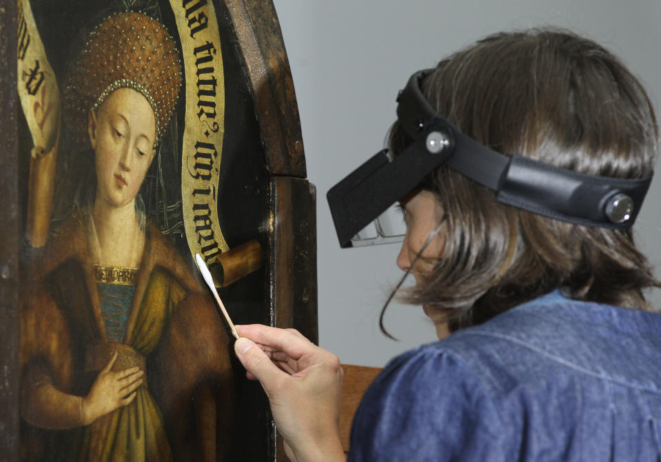 A restorer works on one of the 24 framed panels of the Altarpiece or Adoration of the Mystic Lamb, at the Fine Arts museum in Ghent, Belgium, Thursday, Oct. 11, 2012. The painting, considered to be one of Belgium's masterpieces was completed in 1432 by brothers Hubert and Jan van Eyck, and will be restored over a five-year period. (AP Photo/Yves Logghe)