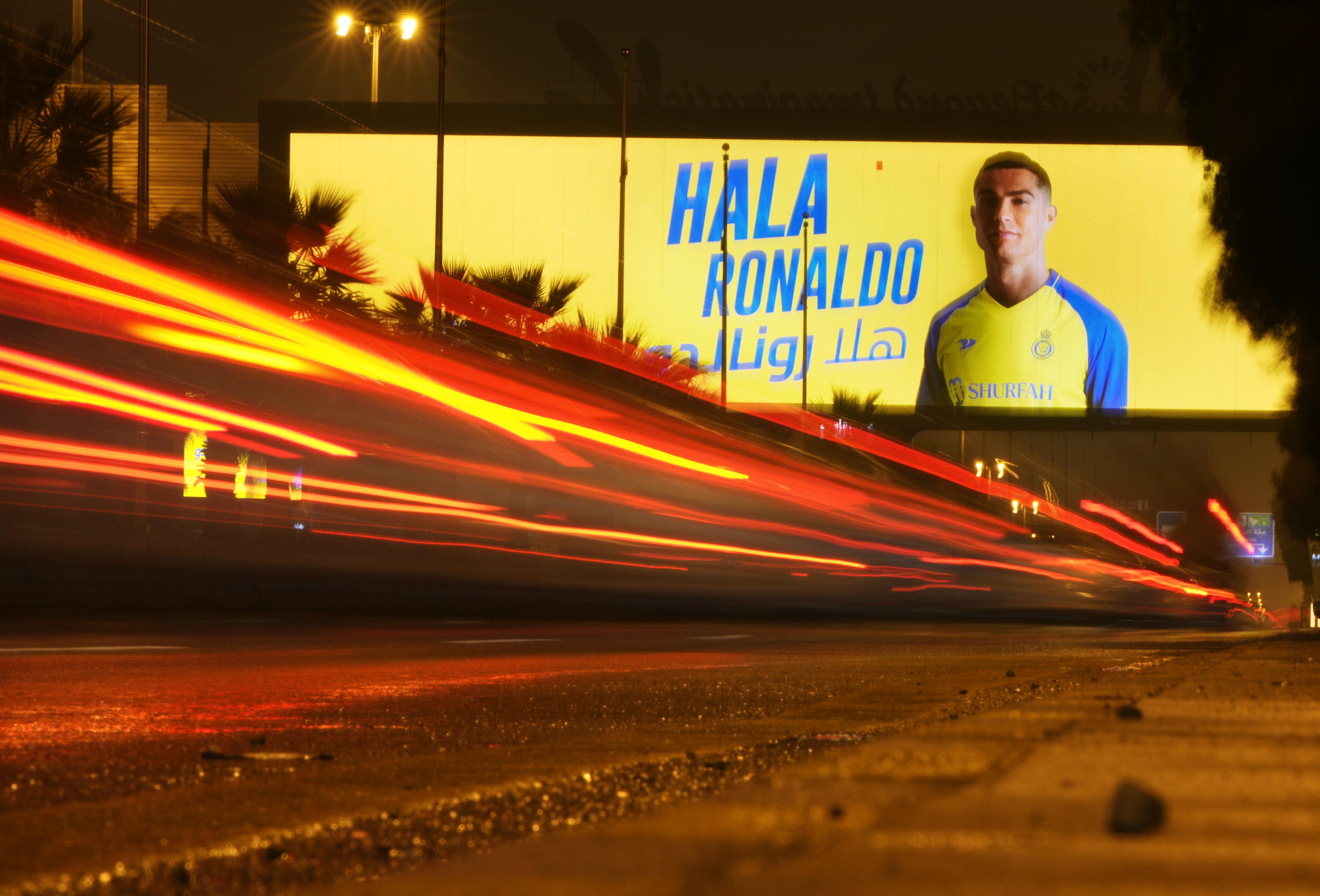 In this photo made with a slow shutter speed, a vehicle passes under a billboard showing Cristiano Ronaldo with Arabic lettering which read, Welcome Ronaldo, in Riyadh, Saudi Arabia, late Monday, Jan 2, 2023. Ronaldo completed a lucrative move to Saudi Arabian club Al Nassr on Friday in a deal that is a landmark moment for Middle Eastern soccer but will see one of Europe's biggest stars disappear from the sport's elite stage. (AP Photo/Amr Nabil)