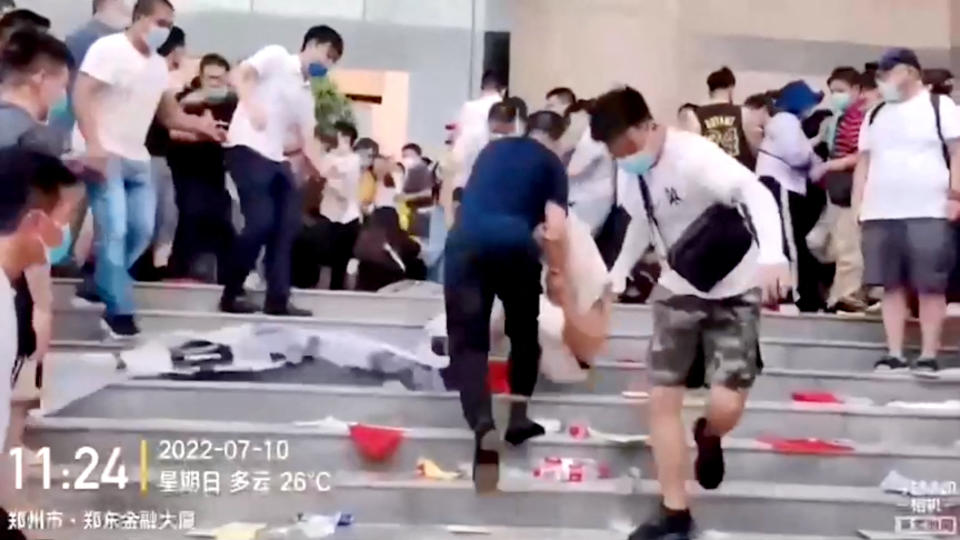 Plain-clothed security personnel drag a demonstrator down a flight of stairs during a protest over the freezing of deposits by some rural-based banks, outside a People's Bank of China building in Zhengzhou, Henan province, China July 10, 2022, in this screengrab from video obtained by REUTERS ATTENTION EDITORS - THIS IMAGE HAS BEEN SUPPLIED BY A THIRD PARTY.