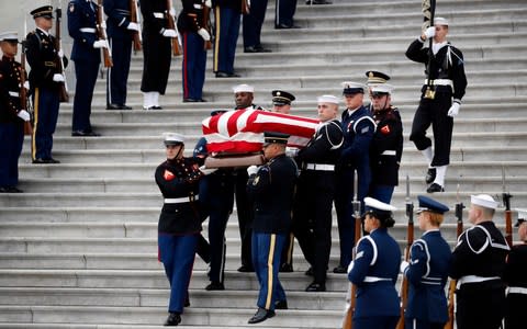 The flag-draped casket of former President George HW Bush is carried by a joint services military honour guard - Credit: AP