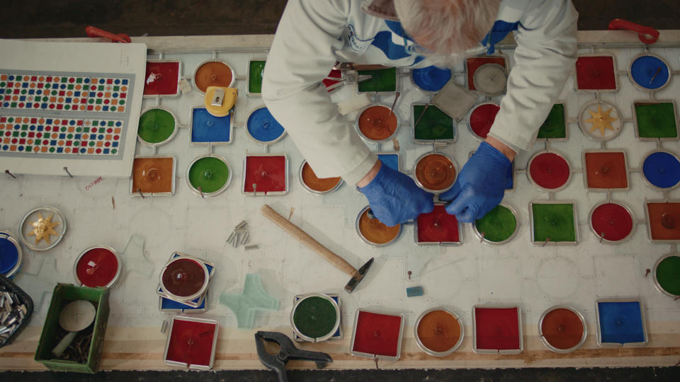 A stained-glass artisan crafts colorful pieces to be installed in the hotel’s pool room.