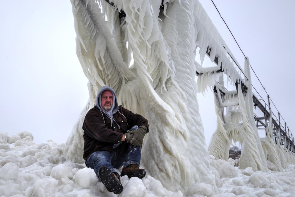 SOUTH HAVEN, MI - JANUARY 8: Mike Kline sitting on the iced pier, on January 8, 2015, in South Haven, Michigan.ICE engulfs a red lighthouse as a fierce winter storm grips South Haven, Michigan. Sharp icicles and surreal formations can be seen hanging from the railings after strong waves crashed onto the piers. After each coating the water quickly freezes to ice and the pier is transformed into a slippery, white wonderland. Weather in the area dipped into the minus figures and froze over Lake Michigan in the beginning of January.PHOTOGRAPH BY Mike Kline / Barcroft MediaUK Office, London.T +44 845 370 2233W www.barcroftmedia.comUSA Office, New York City.T +1 212 796 2458W www.barcroftusa.comIndian Office, Delhi.T +91 11 4053 2429W www.barcroftindia.com