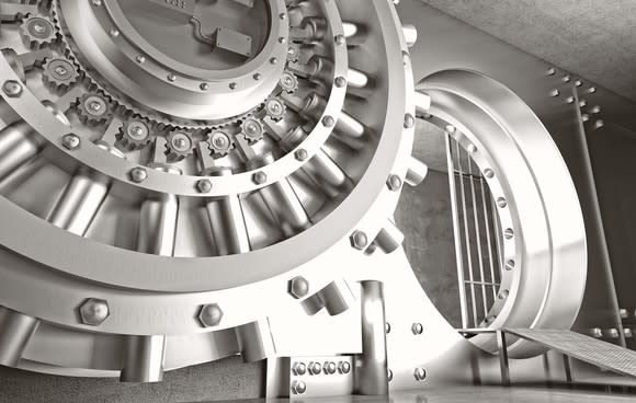 Silver colored bank vault door with vault beyond.