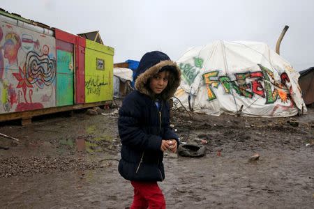 Aida, a nine-year-old Kurdish girl, walks in the mud in the southern part of a camp for migrants called the "jungle", during a rainy winter day in Calais, northern France, February 22, 2016. REUTERS/Pascal Rossignol