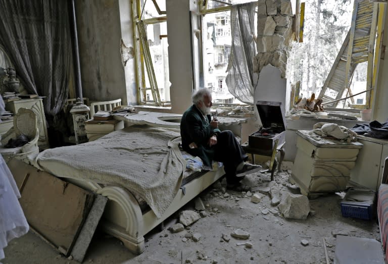 Mohammed Mohiedin Anis, 70, smokes his pipe as he sits in his destroyed bedroom listening to music on his vinyl player in Aleppo's formerly rebel-held al-Shaar neighbourhood